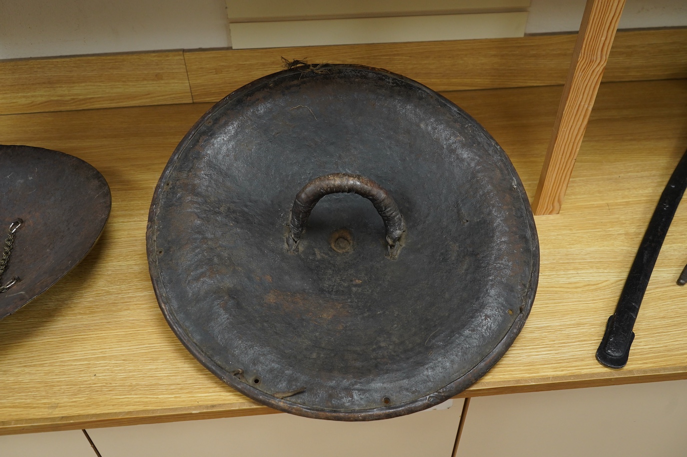 A 19th century Ethiopian/Somali leather shield, 56cm diameter, outside with incised geometric decoration rising to a point, reinforced brim, inside with woven leather handle. Condition - good.